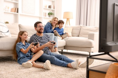 Photo of Happy family playing video games in living room