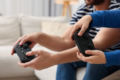 Photo of Father and his son playing video games on sofa indoors, closeup