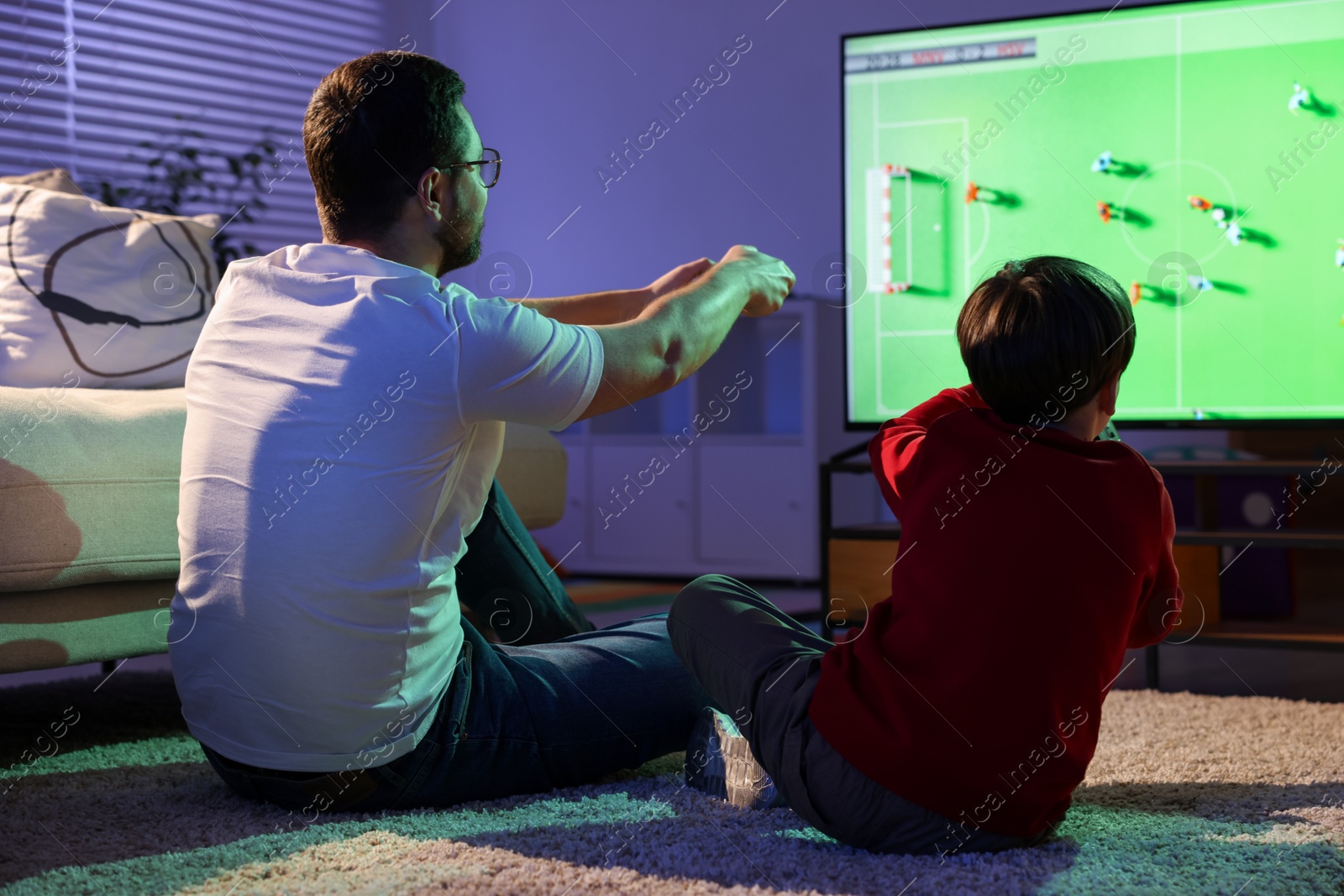 Photo of Father and his son playing video game on floor at home