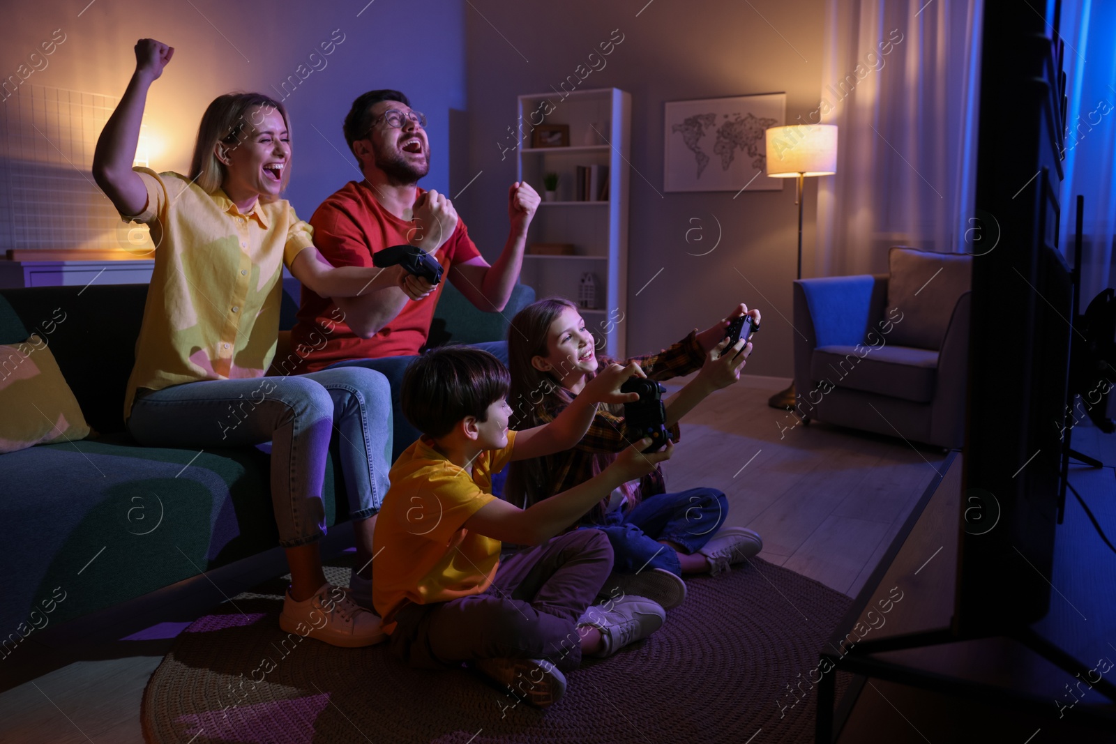 Photo of Happy family playing video games in living room at night