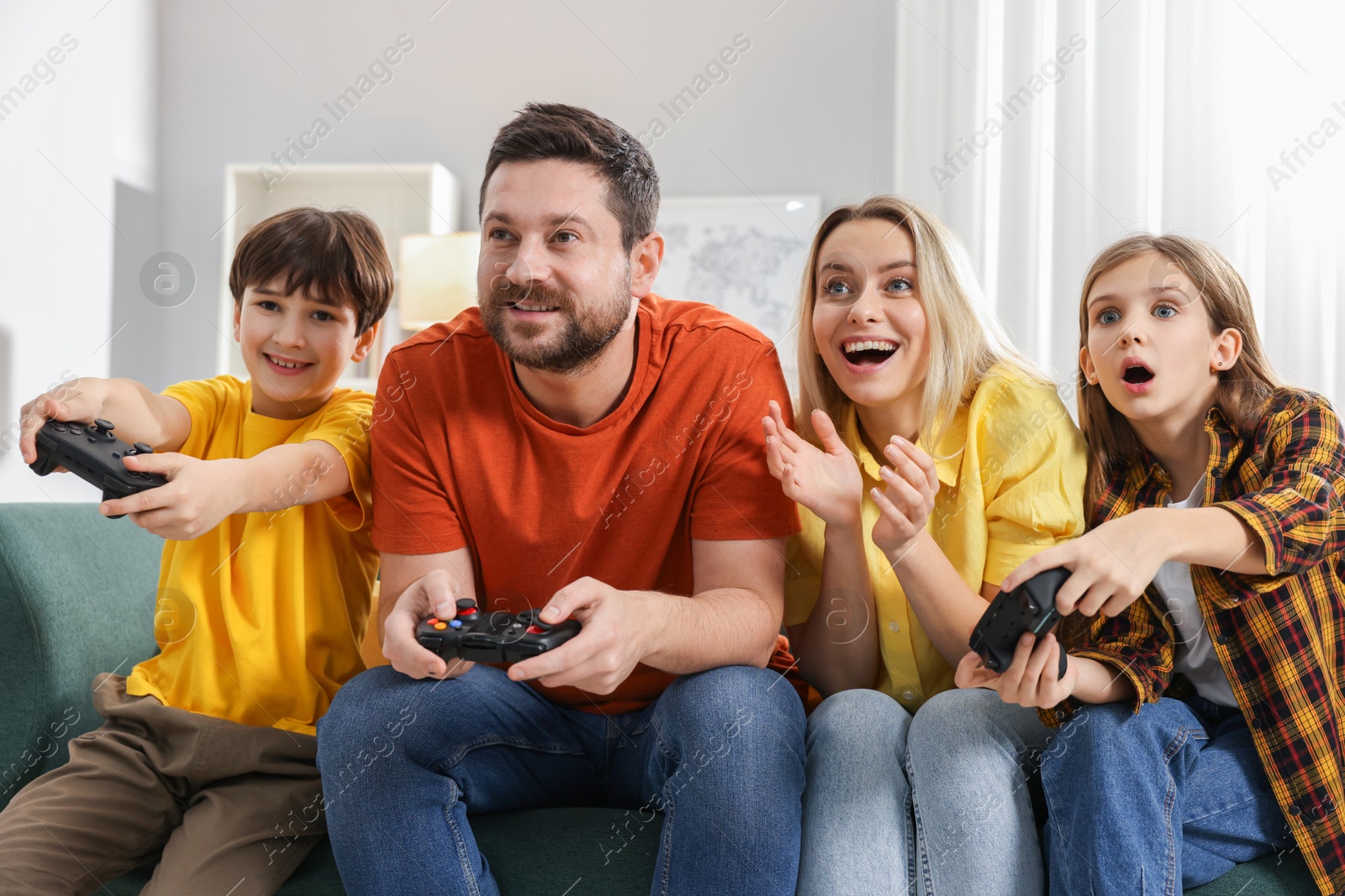 Photo of Happy family playing video games on sofa in living room