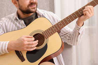 Photo of Relaxing hobby. Smiling man playing guitar at home, closeup