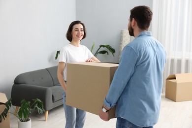 Photo of Moving day. Happy couple carrying box in their new home