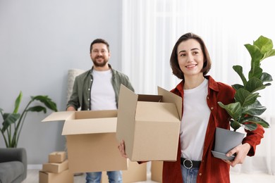 Photo of Moving day. Happy couple with their belongings in new home, selective focus