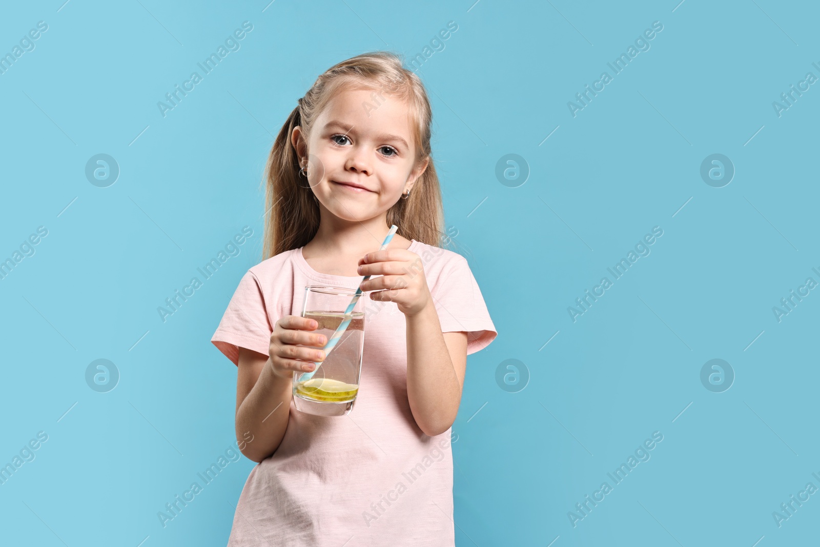 Photo of Girl with glass of lemonade on light blue background. Refreshing drink