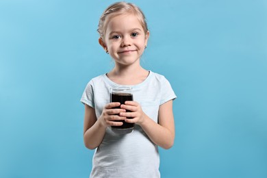 Photo of Girl with glass of refreshing soda drink on light blue background