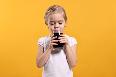 Girl with glass of refreshing soda drink on orange background