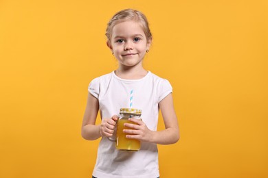 Photo of Girl with mason jar of juice on orange background. Refreshing drink