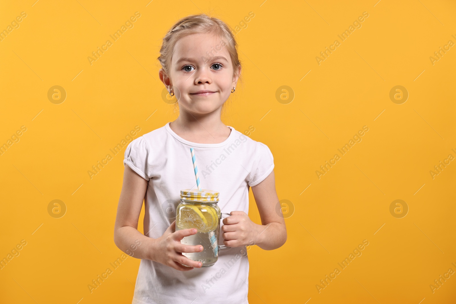 Photo of Girl with mason jar of lemonade on orange background. Refreshing drink