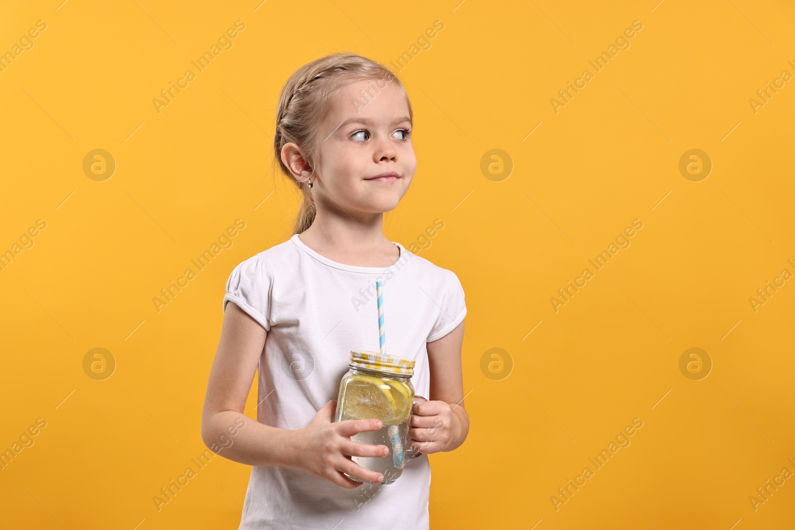 Photo of Girl with mason jar of lemonade on orange background. Refreshing drink