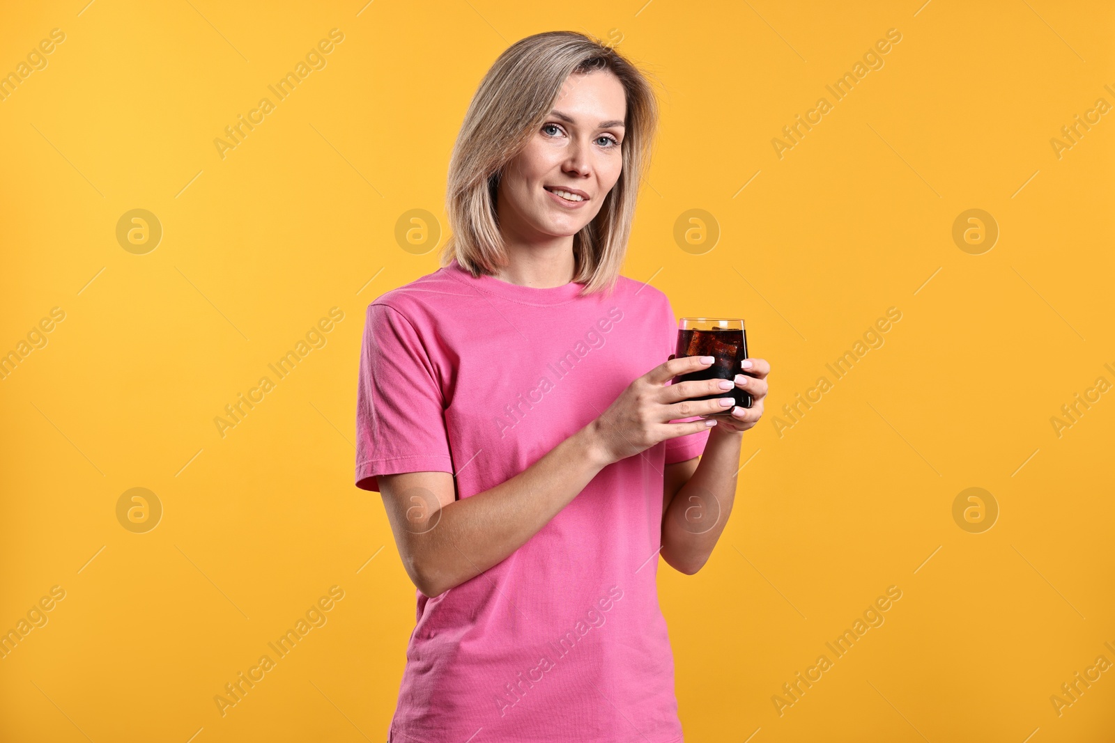 Photo of Woman with glass of refreshing soda drink on orange background