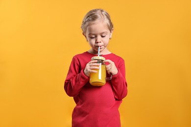 Photo of Girl drinking tasty juice on orange background. Refreshing drink