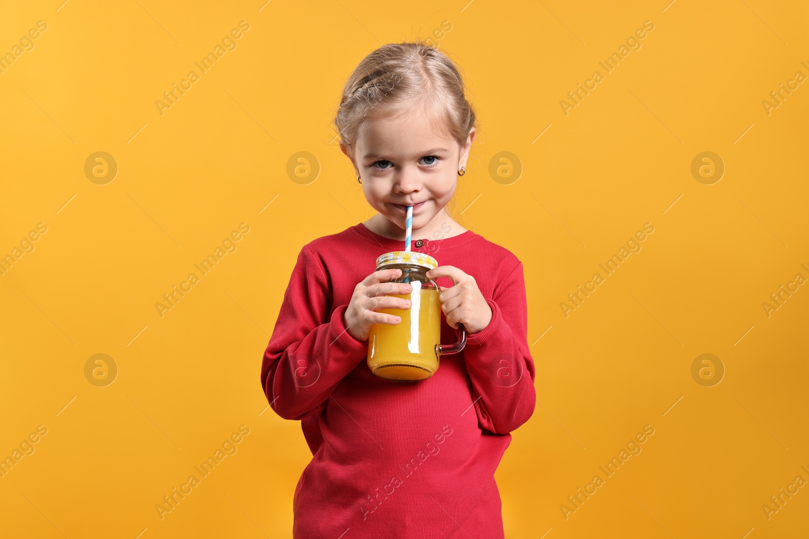 Photo of Girl drinking tasty juice on orange background. Refreshing drink