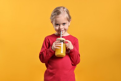 Photo of Girl drinking tasty juice on orange background. Refreshing drink