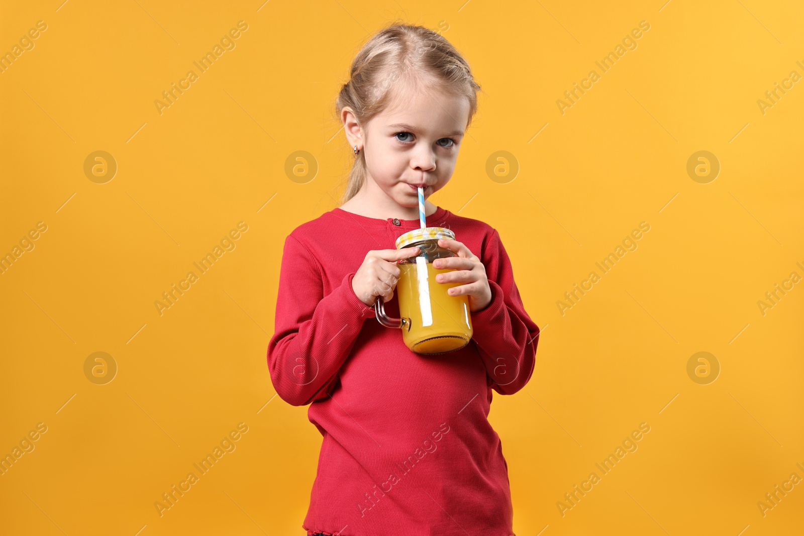 Photo of Girl drinking tasty juice on orange background. Refreshing drink