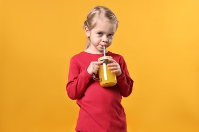 Photo of Girl drinking tasty juice on orange background. Refreshing drink