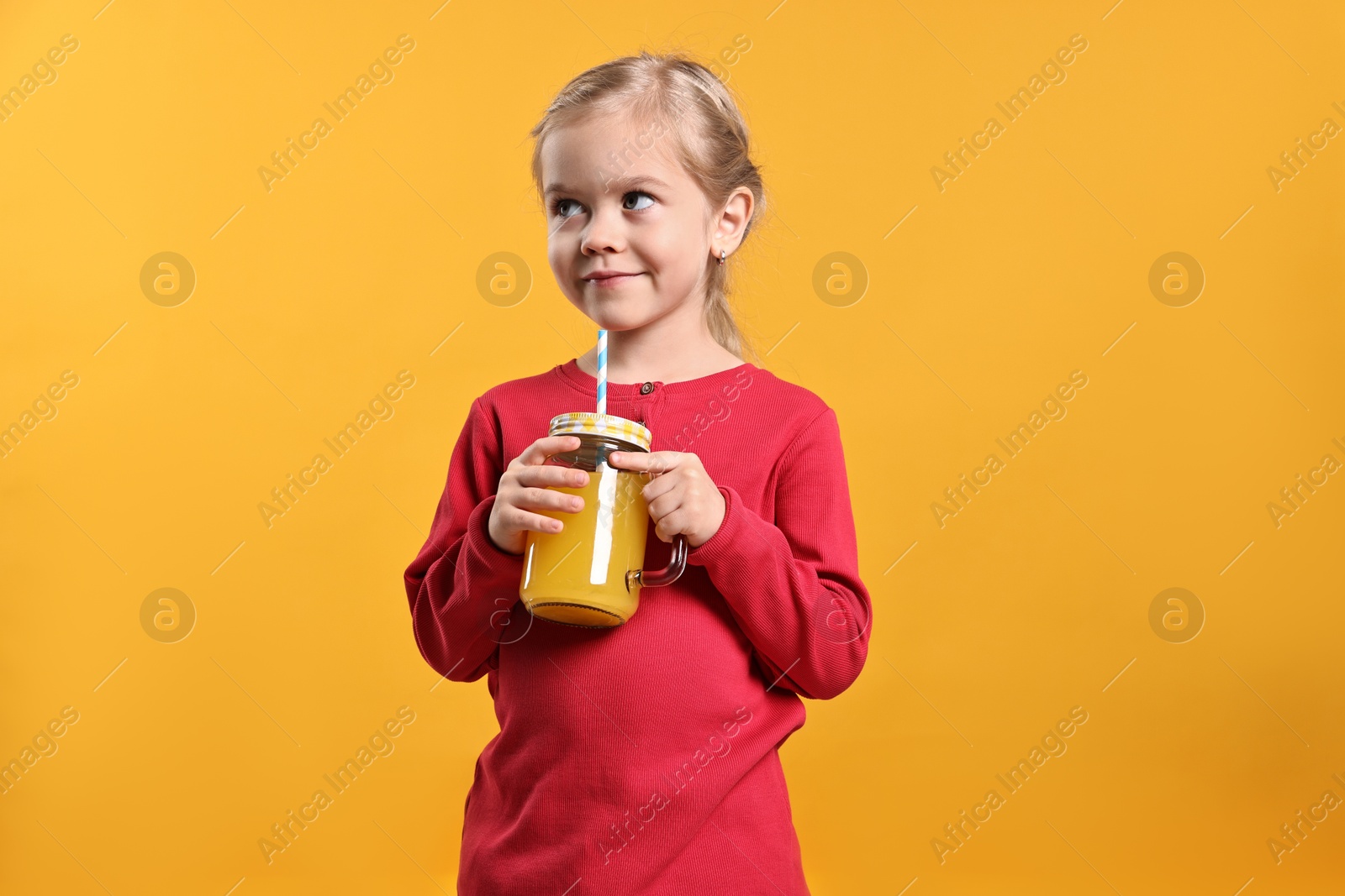 Photo of Girl with mason jar of juice on orange background. Refreshing drink