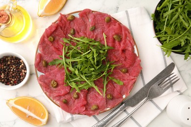 Delicious beef carpaccio served on white marble table, flat lay