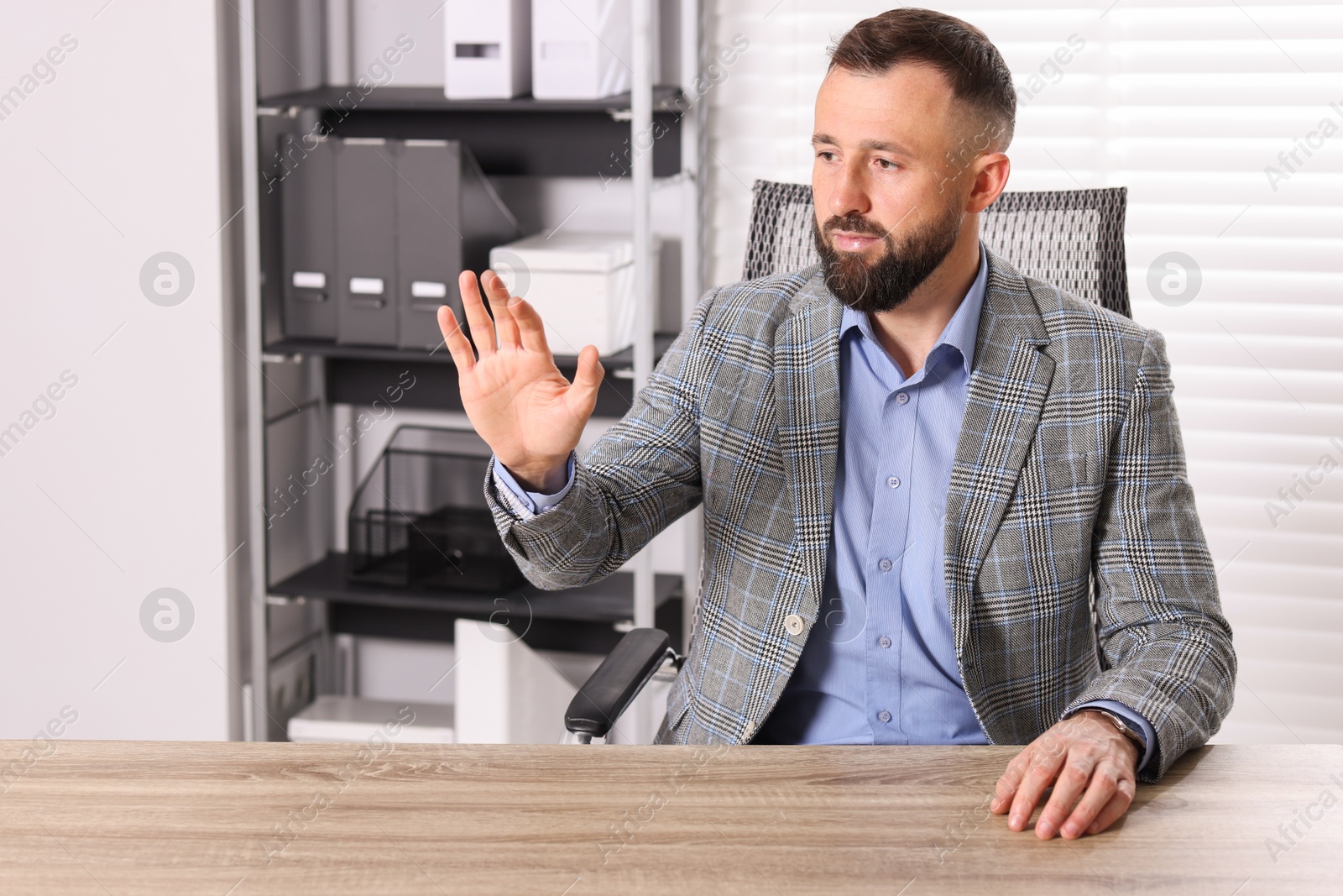 Photo of Man showing something at wooden desk in office, space for text