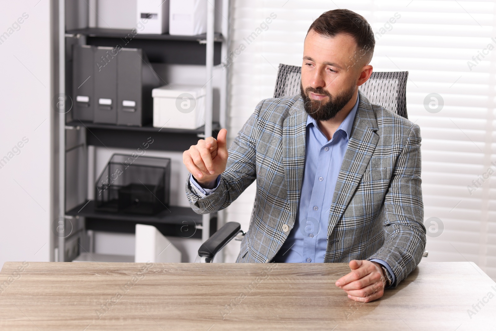 Photo of Man pointing at something at wooden desk in office, space for text