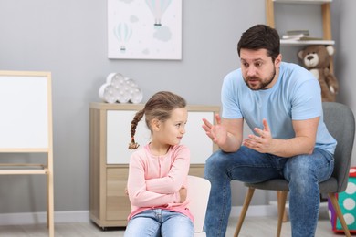 Photo of Resentful little girl and her father arguing at home