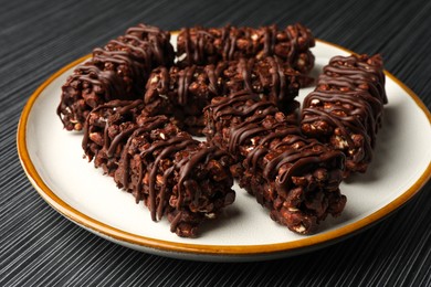 Photo of Delicious chocolate puffed rice bars on dark gray wooden table, closeup