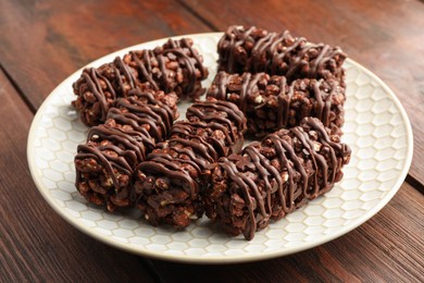 Delicious chocolate puffed rice bars on wooden table, closeup