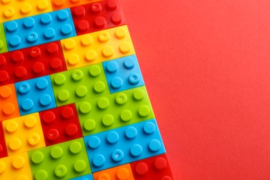 Photo of Construction toy. Colorful building bricks on red background, above view with space for text