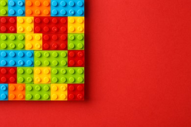 Photo of Construction toy. Colorful building bricks on red background, top view with space for text