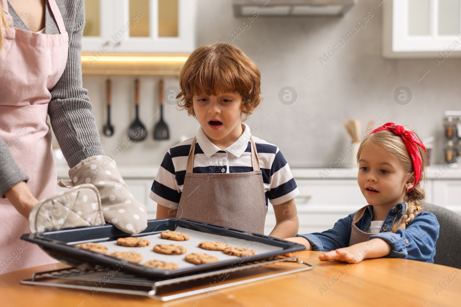 Photo of Mother and her kids with homemade cookies at wooden table in kitchen, closeup