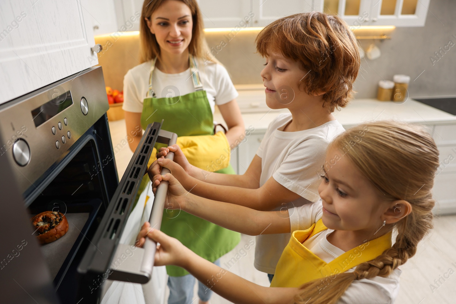 Photo of Mother and her kids baking food in oven indoors, selective focus