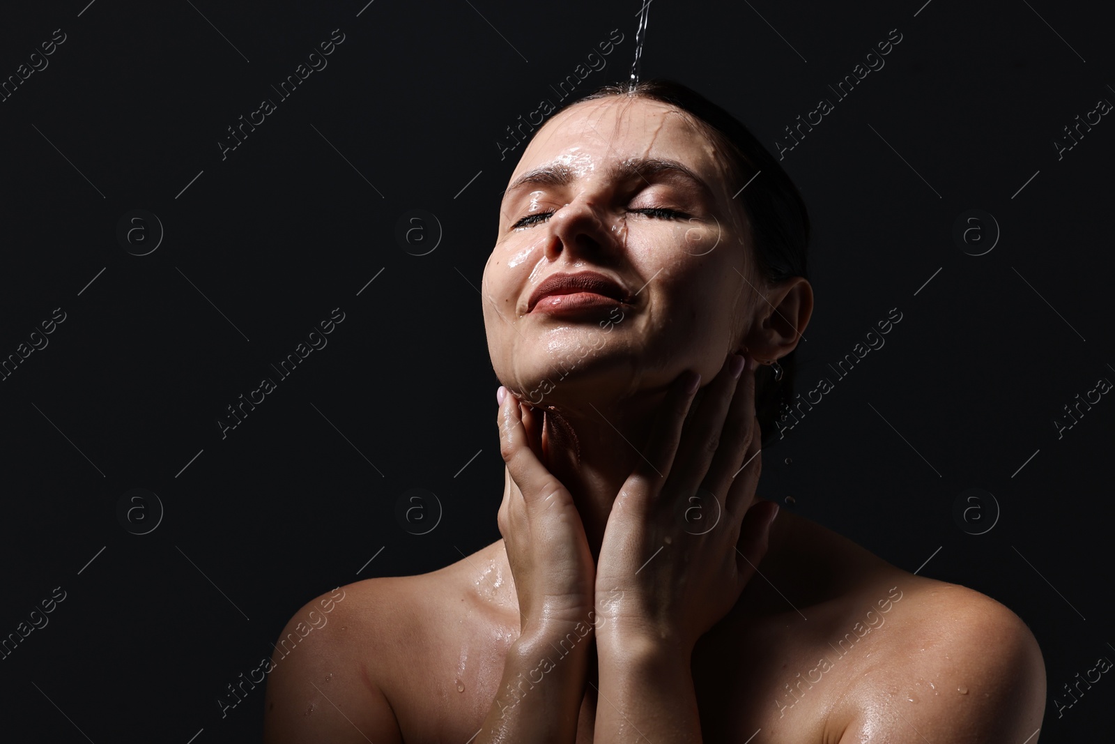 Photo of Attractive woman washing her face on black background