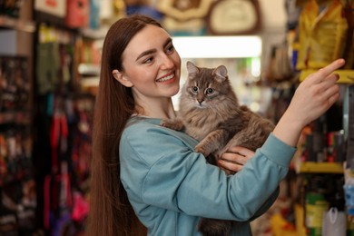 Photo of Happy woman with her cute cat in pet shop