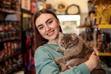 Photo of Happy woman with her cute cat in pet shop