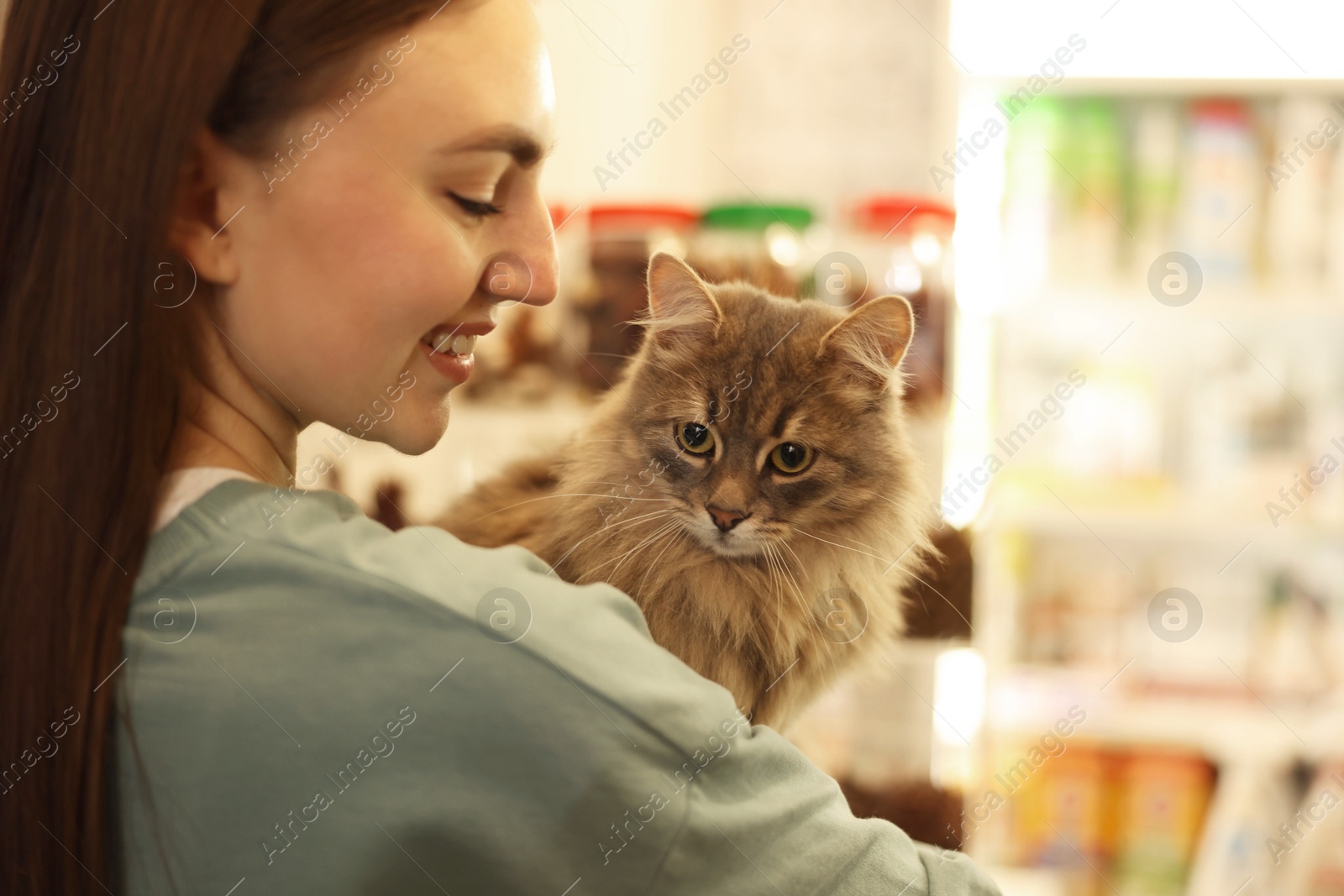 Photo of Woman with her cute cat in pet shop, closeup