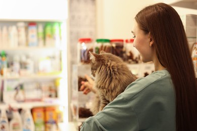 Photo of Woman with her cute cat in pet shop. Space for text