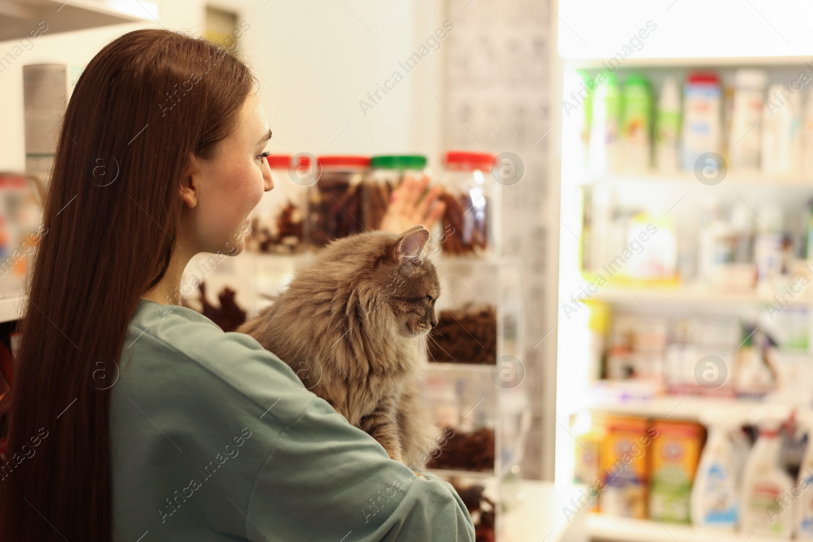 Photo of Woman with her cute cat in pet shop. Space for text