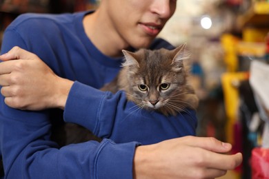 Photo of Man with his cute cat in pet shop, closeup