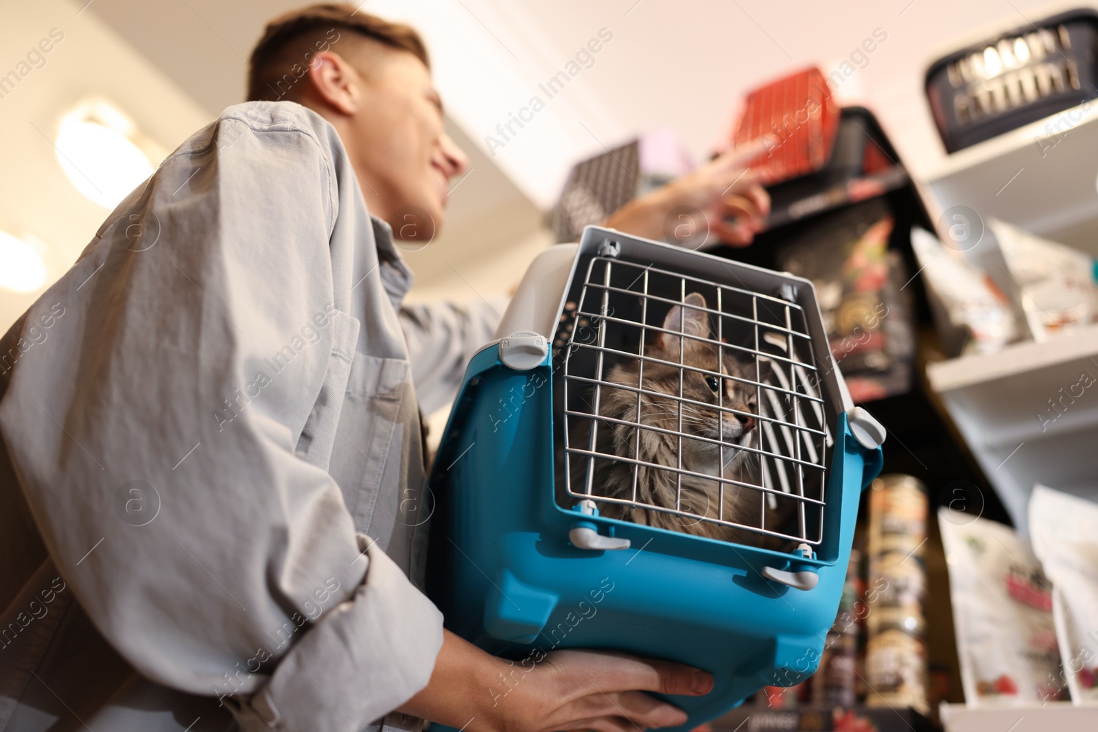 Photo of Man with his cute cat in pet shop, low angle view