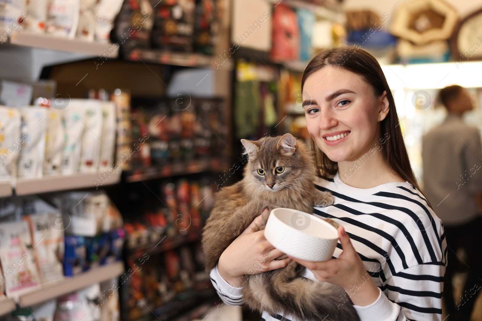 Photo of Woman with her cute cat and feeding bowl in pet shop. Space for text