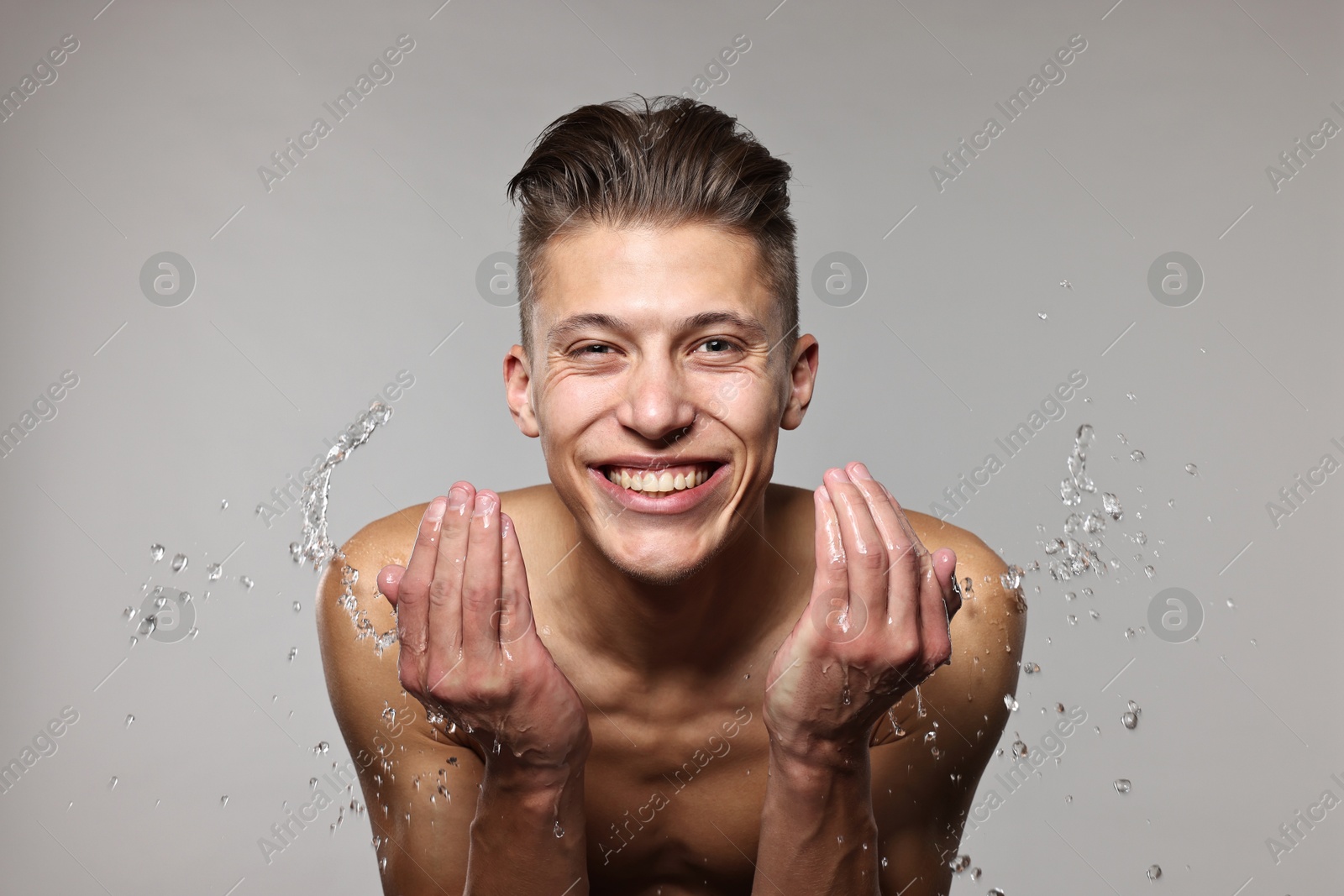 Photo of Smiling man washing his face on grey background