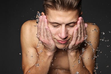 Handsome man washing his face on black background