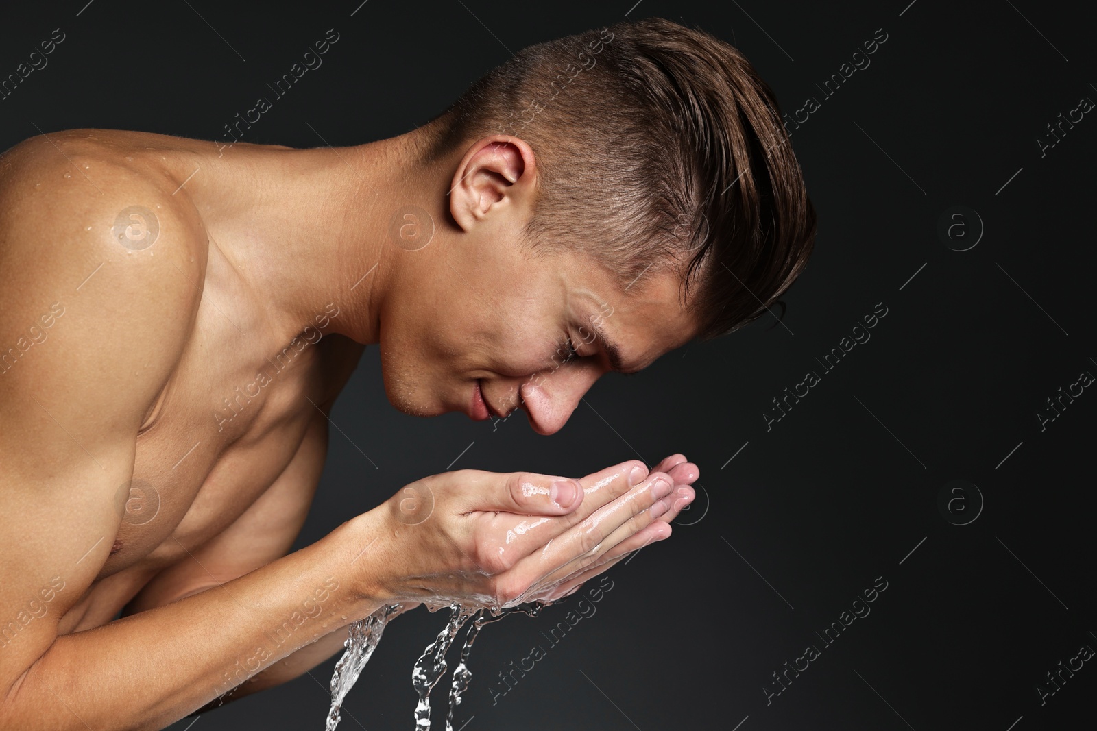 Photo of Handsome man washing his face on black background