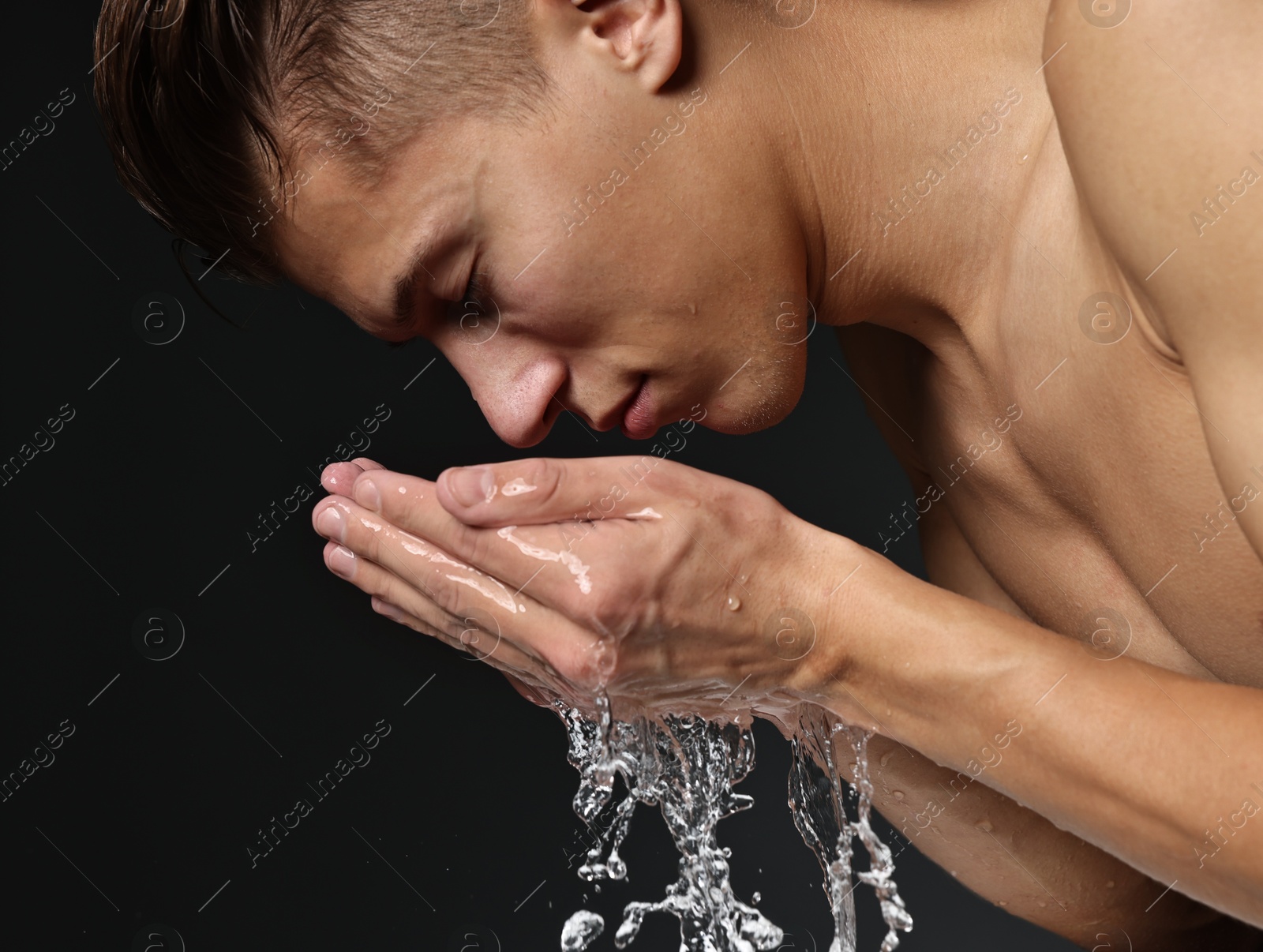 Photo of Handsome man washing his face on black background