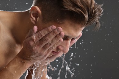 Photo of Man washing his face on grey background