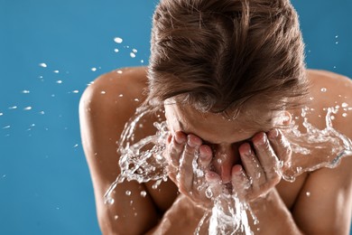 Photo of Man washing his face on blue background