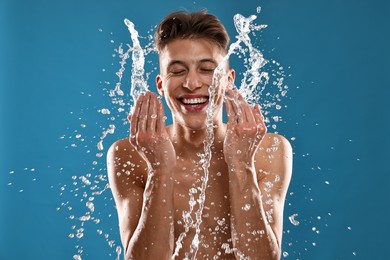 Photo of Smiling man washing his face on blue background