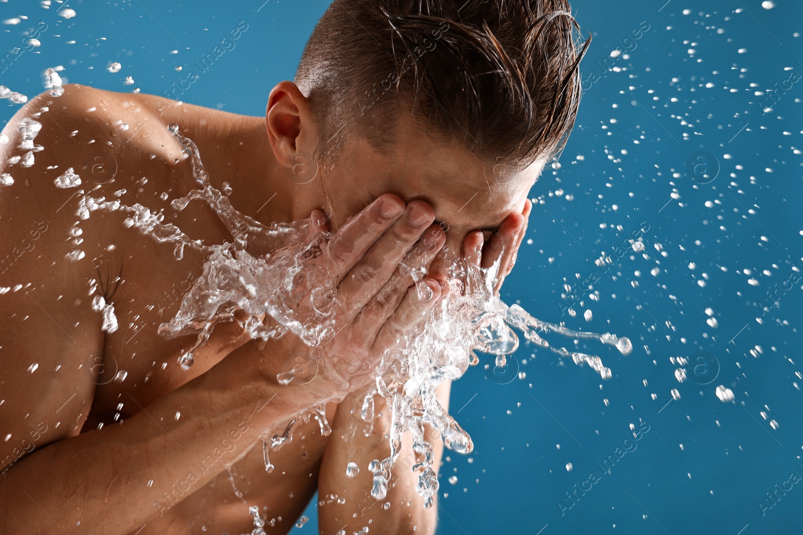 Photo of Man washing his face on blue background