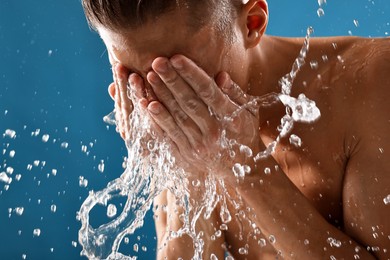 Photo of Man washing his face on blue background