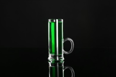 Photo of Absinthe in shot glass on black mirror surface